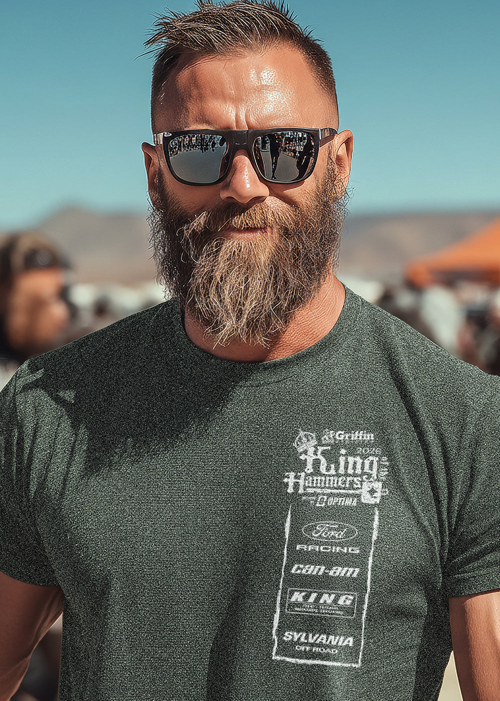 Man wearing sunglasses and a branded t-shirt with a desert background